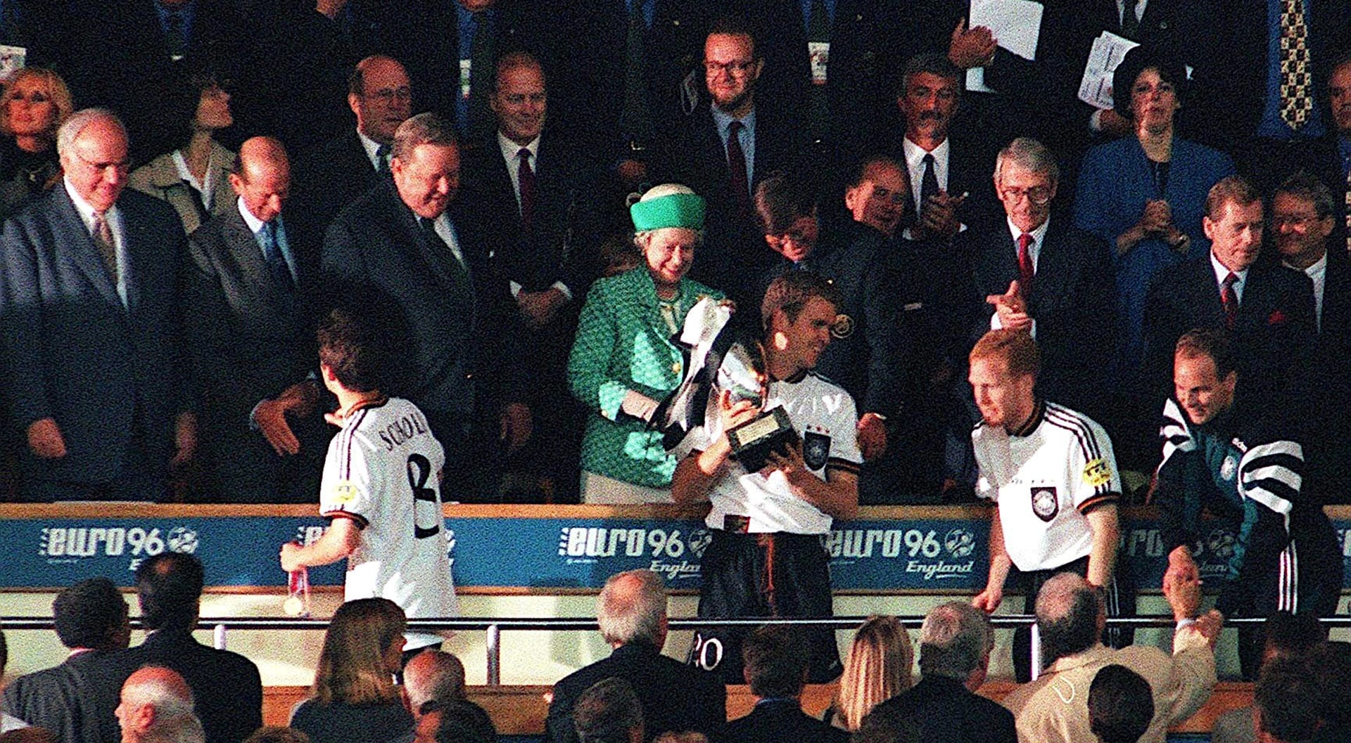 Oliver Bierhoff se neslušně otáčí zády ke královně Alžbětě II. na londýnském stadionu ve Wembley po vítězném finále Euro 1996. Zcela vpravo v lóži Ivan Kočárník, tehdejší ministr financí, vedle něj zleva prezident Václav Havel. Po jeho boku britský premiér John Major. Zleva od královny stojí Lennart Johansson, bývalý prezident UEFA, královnin manžel princ Philip a zcela vlevo německý kancléře Helmut Kohl.