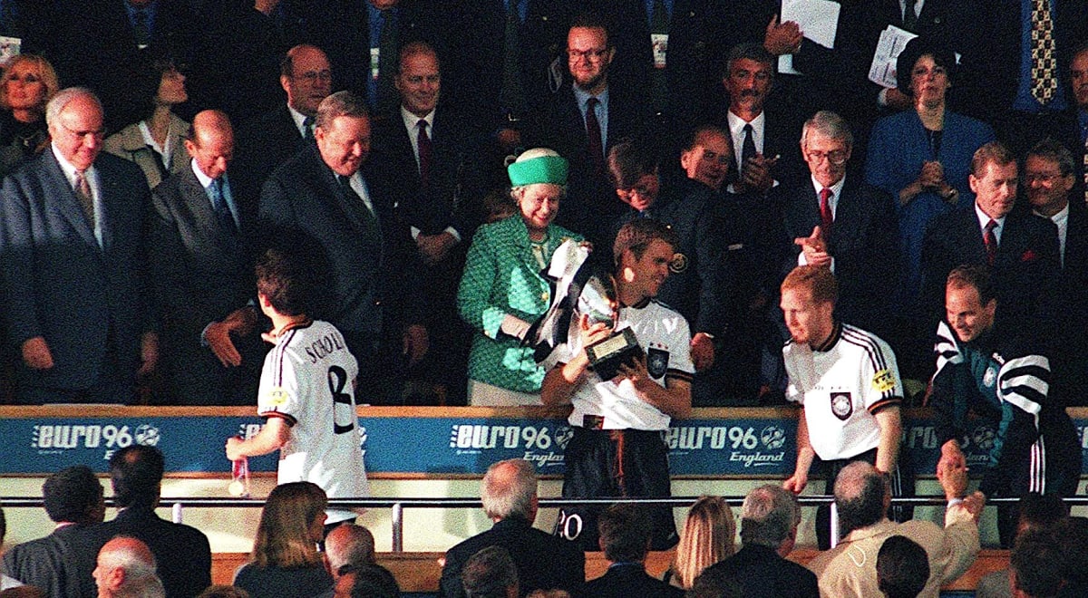 Oliver Bierhoff se neslušně otáčí zády ke královně Alžbětě II. na londýnském stadionu ve Wembley po vítězném finále Euro 1996. Zcela vpravo v lóži Ivan Kočárník, tehdejší ministr financí, vedle něj zleva prezident Václav Havel. Po jeho boku britský premiér John Major. Zleva od královny stojí Lennart Johansson, bývalý prezident UEFA, královnin manžel princ Philip a zcela vlevo německý kancléře Helmut Kohl.