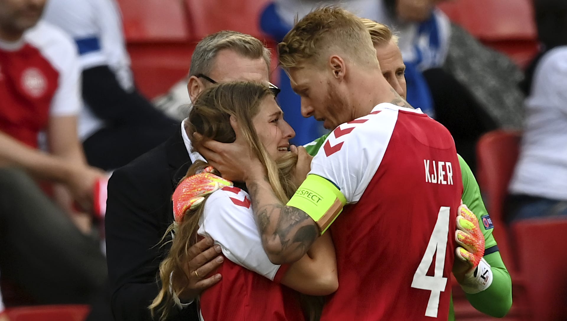 Dánský kapitán Simon Kjaer utěšuje u postranní čáry Sabrinu Kvistovou Jensenovou, manželku spoluhráče Christiana Eriksena, který zkolaboval 12. června 2021 při zápase mistrovství Evropy proti Finsku. 