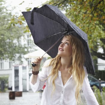 Dívka pod deštníkem při dešti.