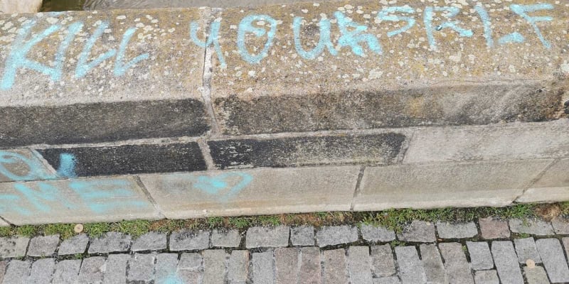 Neznámý vandal posprejoval část Karlova mostu, nápisy jsou na zábradlí i soše.