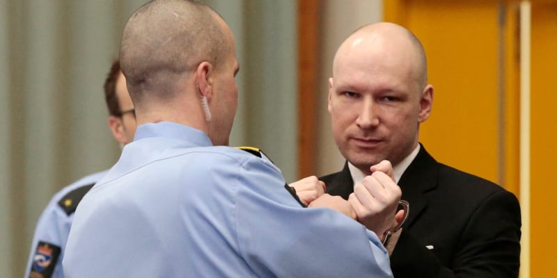 Policista sundavá pouta Andersi Breivikovi u soudu.