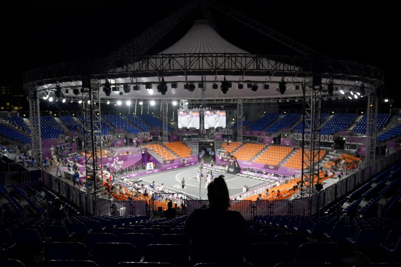 Člověk sedící mezi převážně prázdnými tribunami, když Spojené státy a Mongolsko hrají v Aomi Urban Sports parku během basketbalového zápasu žen 3 na 3.