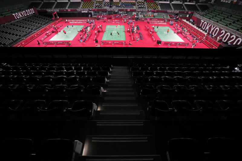 Hráči badmintonu soutěží v řadách prázdných sedadel na Musashino Forest Sport Plaza.
