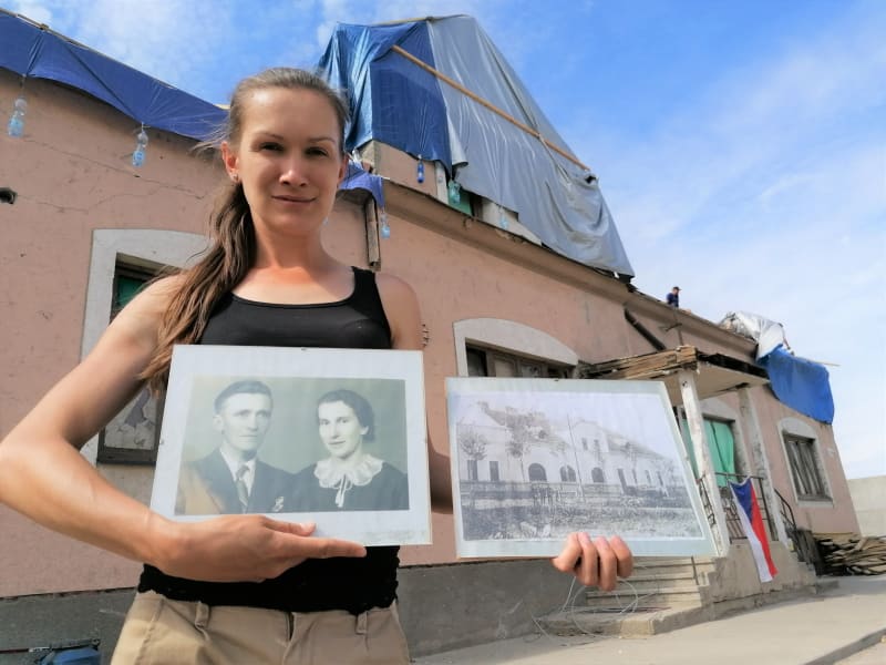 Aneta Stibůrková před svou hospodou v Lužicích, kterou zdevastovalo tornádo. V ruce drží portréty předků, kteří restauraci vlastnili před komunistickým znárodněním. A také předválečný snímek podniku.