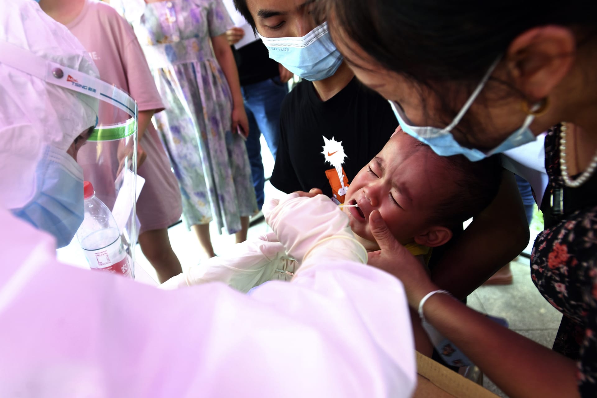 Lékař provádí test dítěti v jedné z koronavirem zasažených čtvrtí ve Wu-chanu