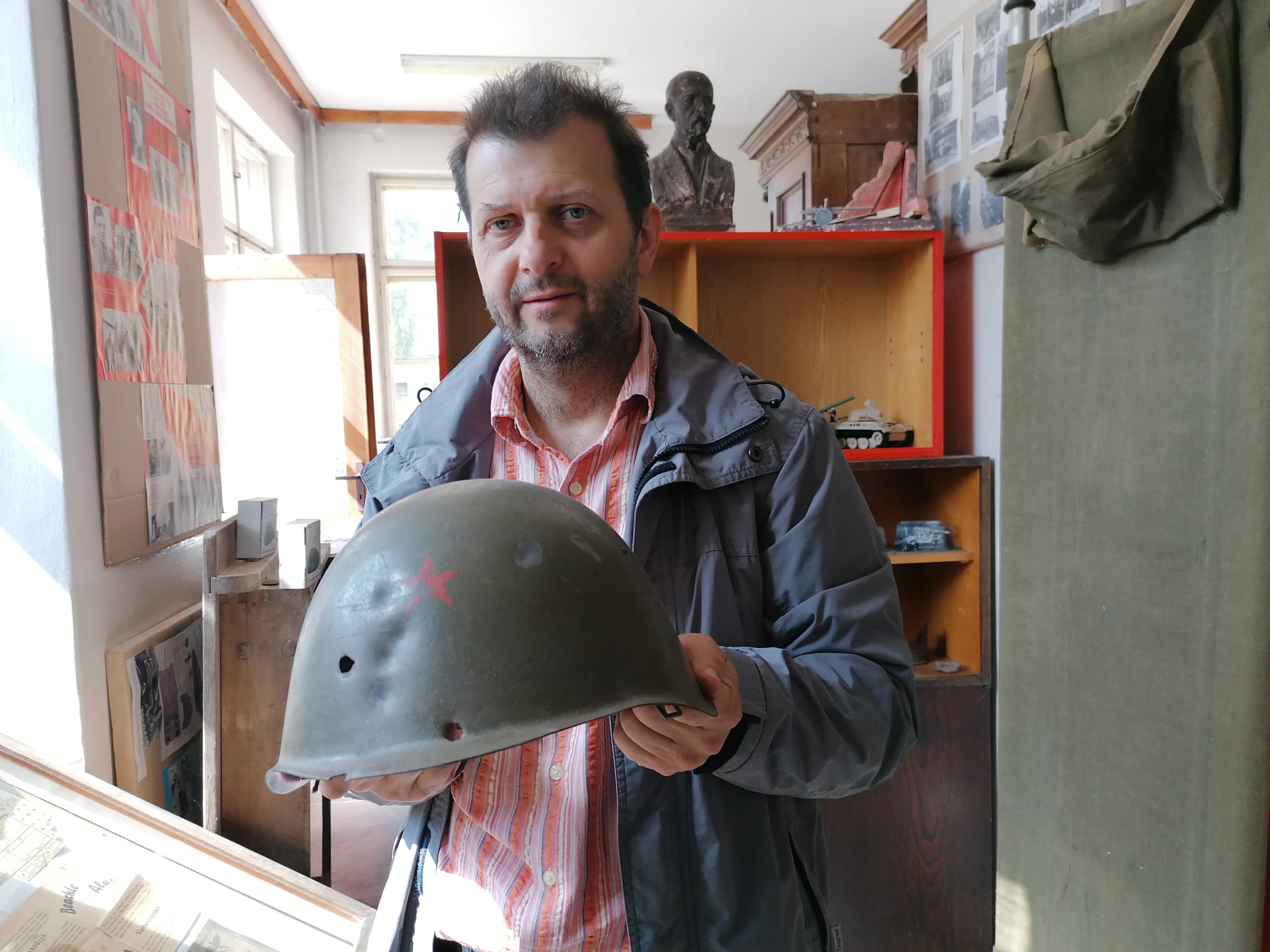 Osoblažské muzeum s nálezy z války. Marian Hrabovský ukazuje prostřílenou ruskou helmu z bitvy o Osoblahu, do muzea brzy přibude nalezený bitevník Il-2 šturmovik.