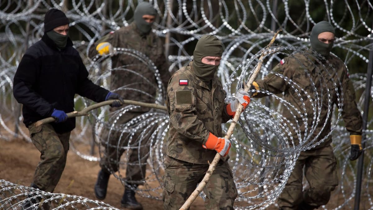 Polští vojáci budují žiletkový plot na hranici s Běloruskem.