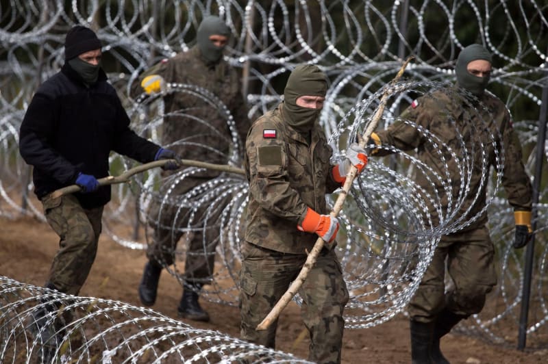 Polští vojáci budují žiletkový plot na hranici s Běloruskem.