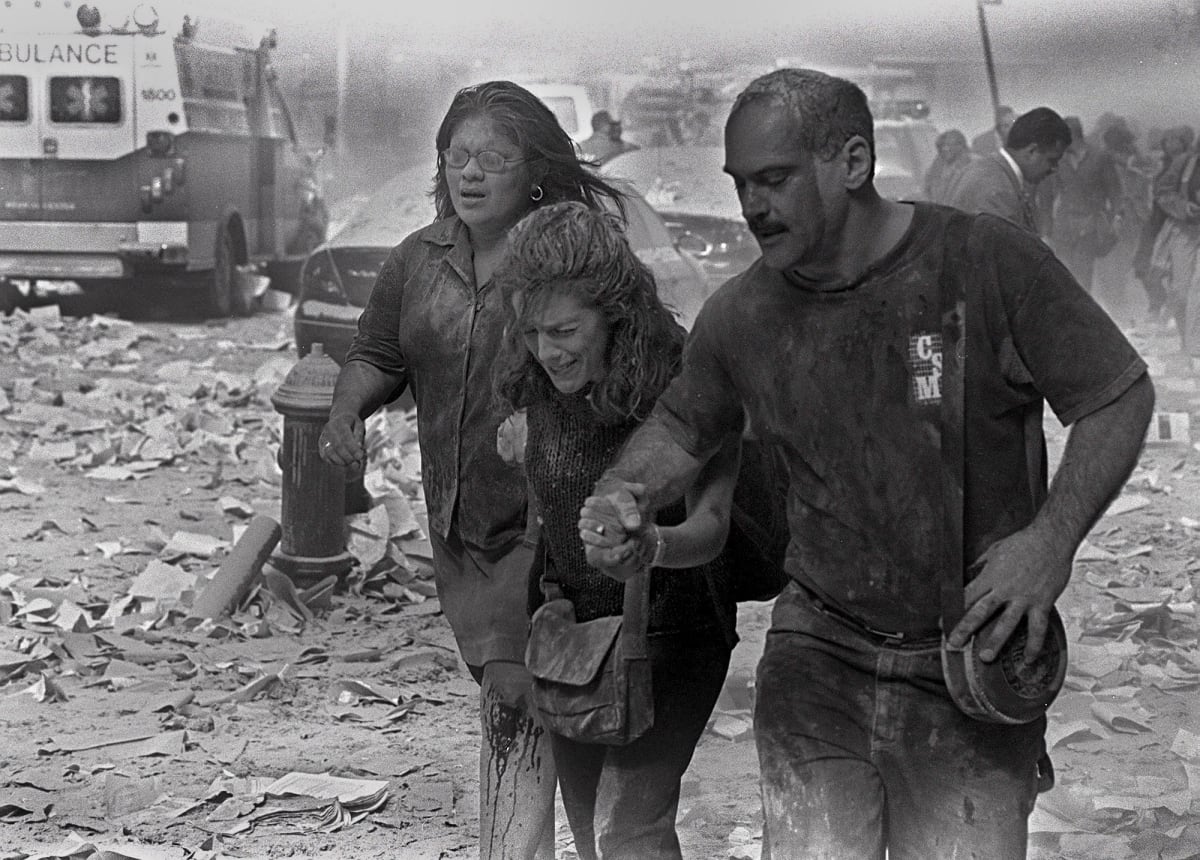Julie McDermottová (uprostřed) kráčí s dalšími oběťmi, které se prodírají mezi troskami poblíž Světového obchodního centra v New Yorku. 
