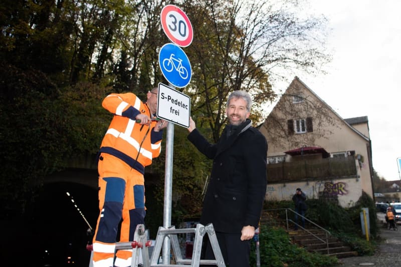 Starosta města Tübingen Boris Palmer pózuje u montáže značky před novým tunelem určeným pro cyklisty a elektromopedy.
