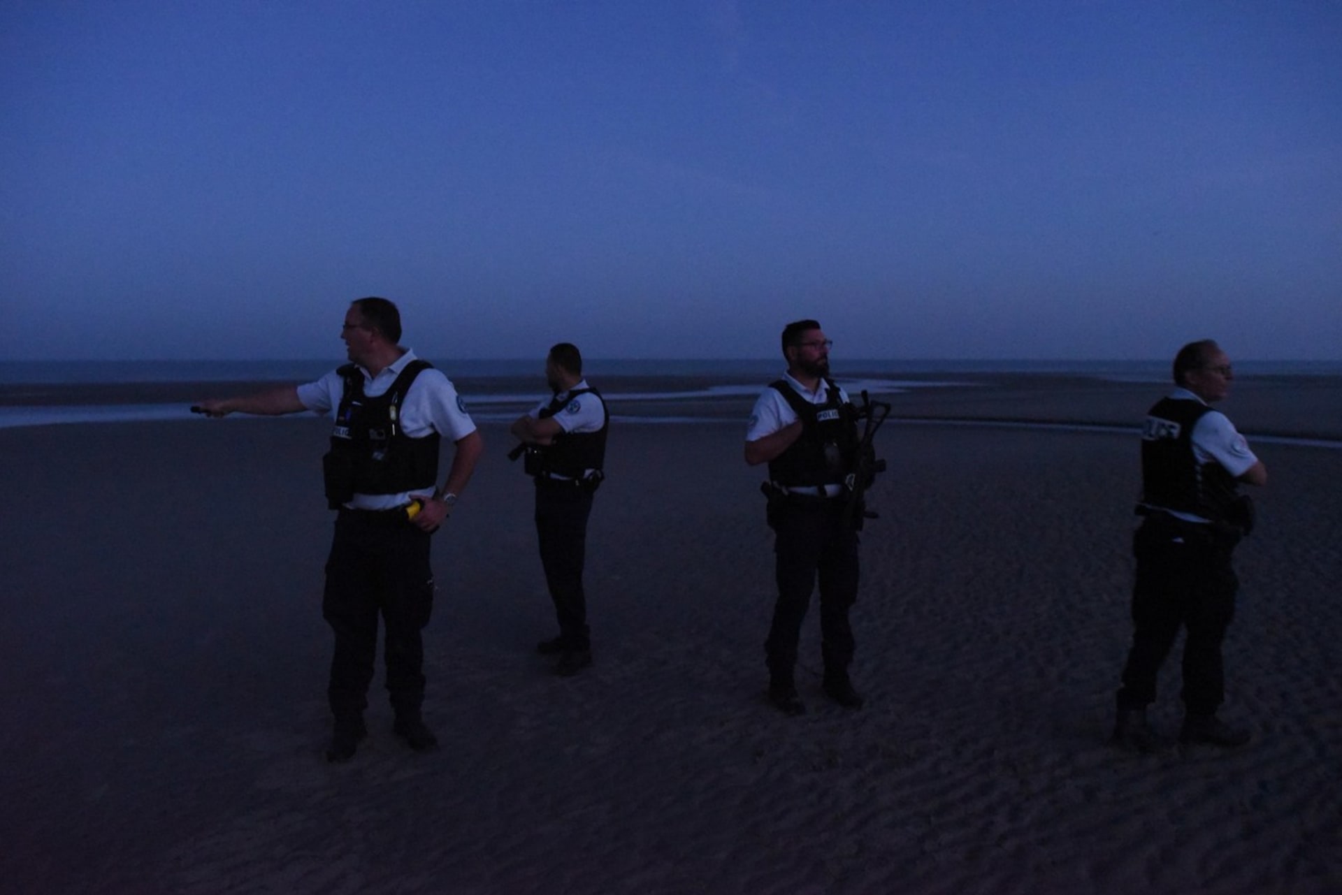 Francouzští policisté hlídkují na pláži a snaží se zabránit nelegálním migrantům v cestě do Británie