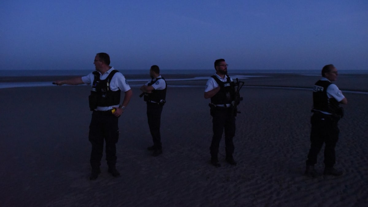 Francouzští policisté hlídkují na pláži a snaží se zabránit nelegálním migrantům v cestě do Británie