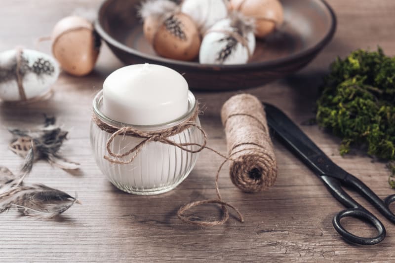 Svícen na svátečně nazdobený velikonoční stůl: Lněný provázek omotejte kolem vajíčka s peříčkem a uvažte na pěknou mašličku Stejně ozdobte i skleničku na svíčku.