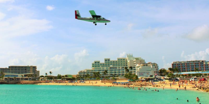 Pilot prolétá nad pláží před přistáním na letišti na Svatém Martinu.