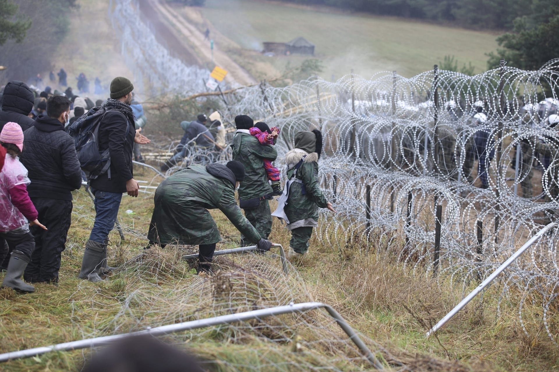 Stovky migrantů se snaží poškodit plot s ostnatým drátem na bělorusko-polské hranici.
