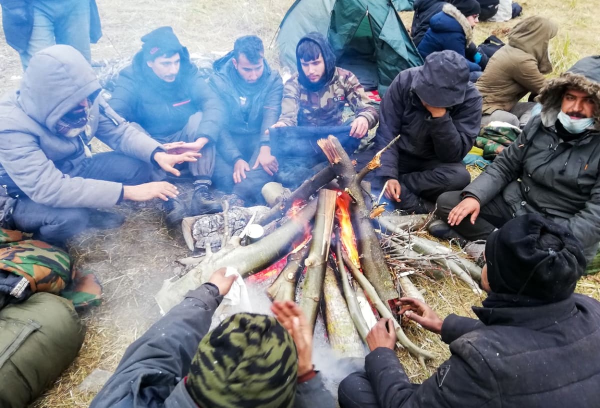 Migranti kácejí lesy a snaží se v chladném počasí zahřát.