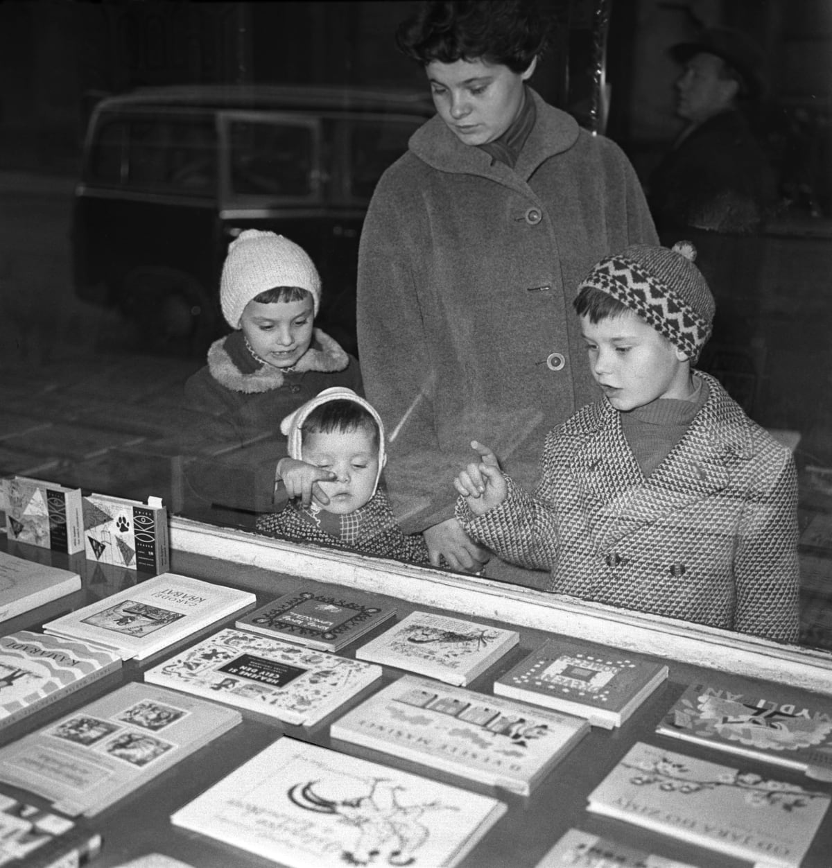 Děti s vybírají vánoční dárky u výlohy. Psal se rok 1961.
