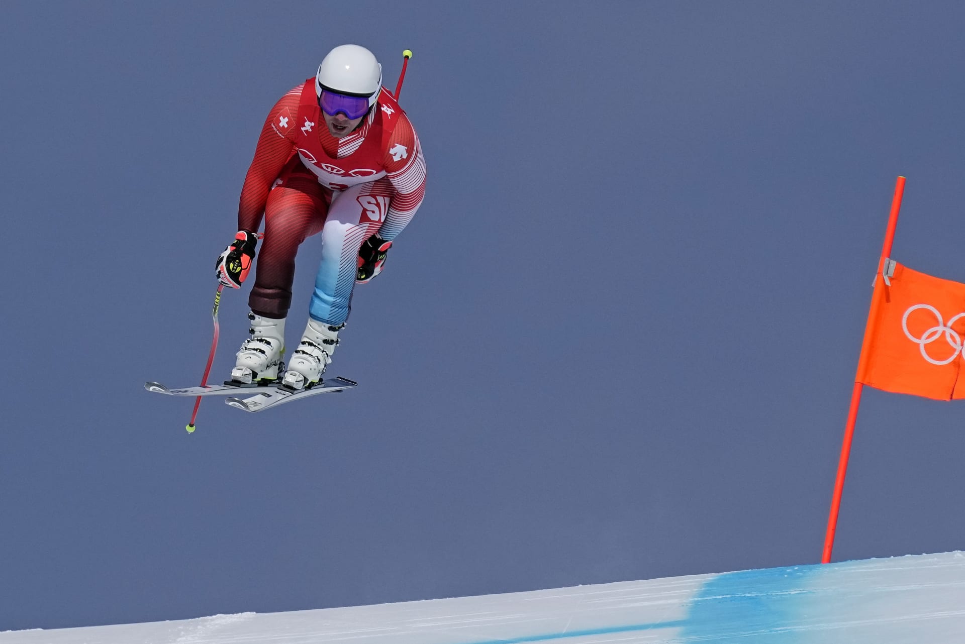 Švýcarský sjezdař Beat Feuz letí po skoku při závodě na olympijských hrách 2022, který vyhrál s náskokem jedné desetiny. 