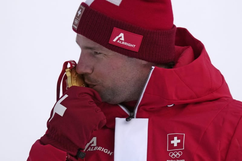 Švýcarský lyžař Beat Feuz líbá zlatou medaili ze závodu ve sjezdu na olympijských hrách 2022.