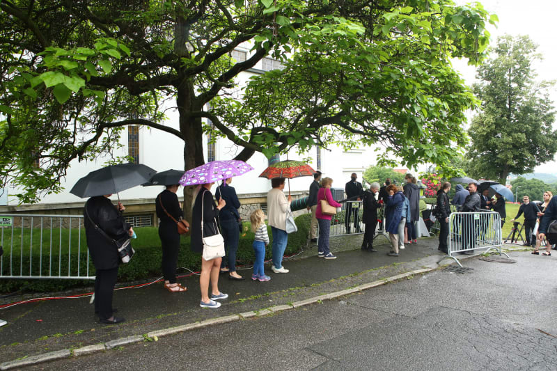 Lidé čekají v dešti, aby se mohli rozloučit
