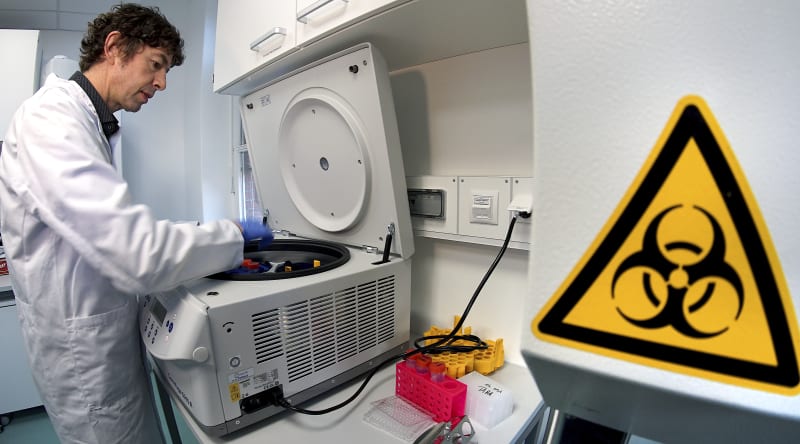 Německý virolog a poradce německé vlády Christian Drosten vkládá materiál od testovacího zařízení v berlínské nemocnici Charité.