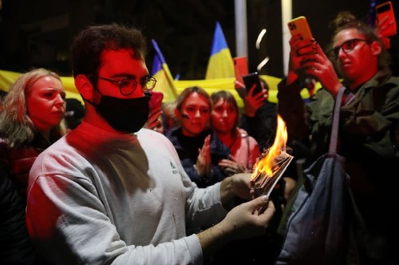 Proukrajinský demonstrant pálí svůj ruský pas během protestu proti nedávné eskalaci mezi Ruskem a Ukrajinou před ruským velvyslanectvím v Tel Avivu