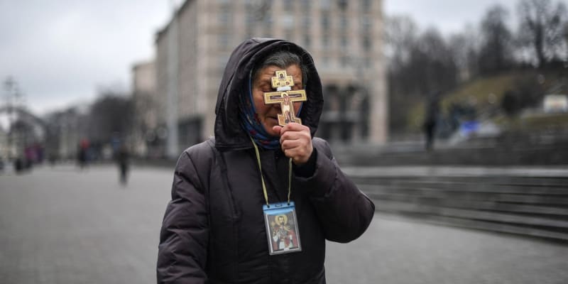Věřící žena drží kříž při modlitbě na náměstí Nezávislosti v Kyjevě 24. února 2022 ráno.