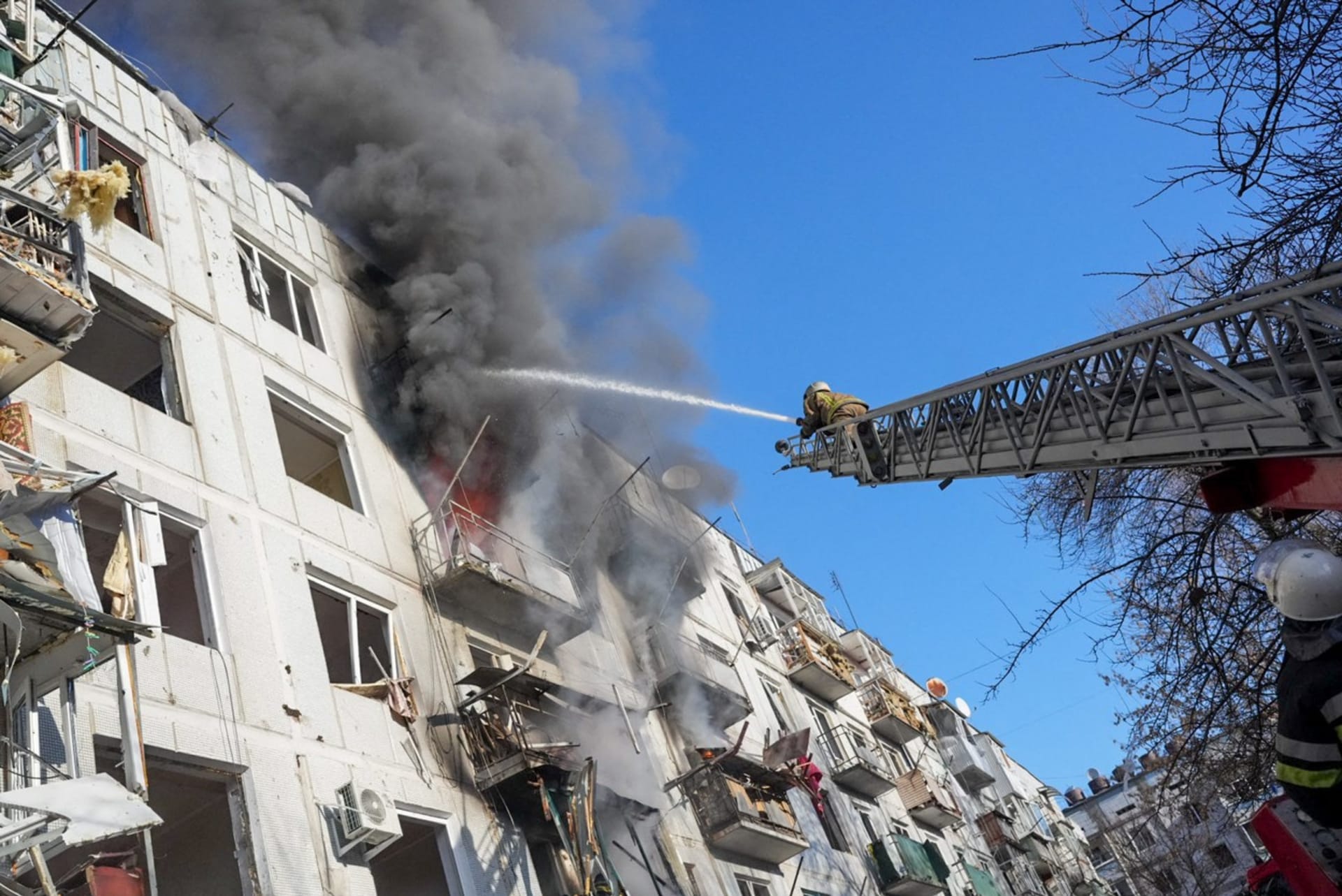 Ukrajinští hasiči se snaží uhasit požár po náletu na obytný komplex v Charkově. 