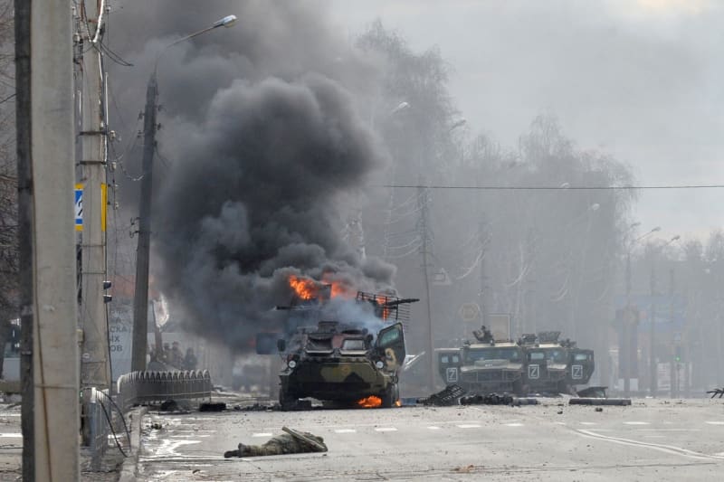 Ruský obrněný transportér (APC) hořící vedle těla neidentifikovaného vojáka během bojů s ukrajinskými ozbrojenými silami v Charkově