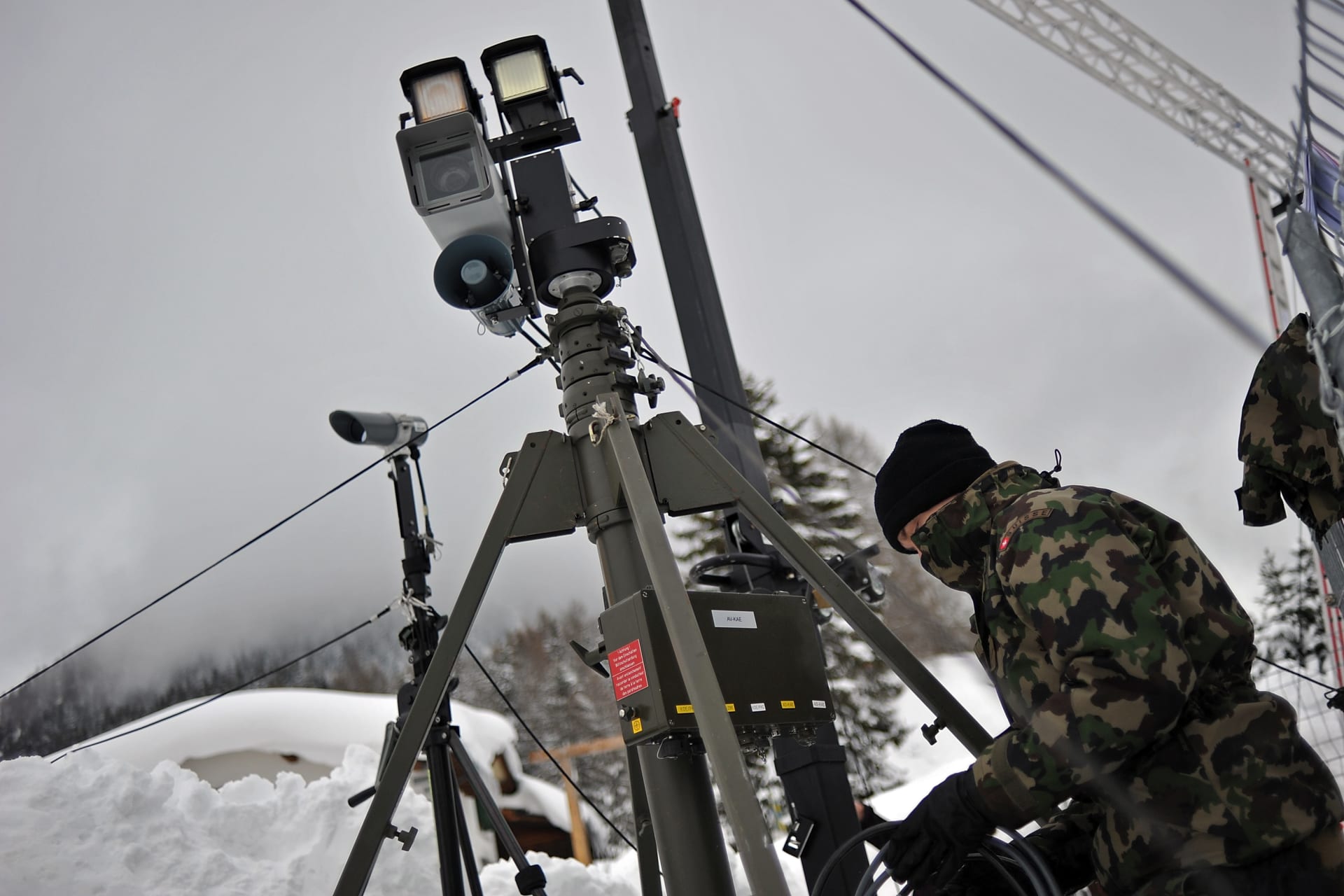 Maskovaný voják speciální švýcarské jednotky AAD-10 instaluje pozorovací zařízení. 
