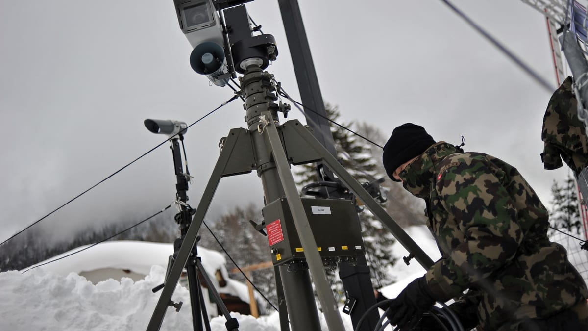 Maskovaný voják speciální švýcarské jednotky AAD-10 instaluje pozorovací zařízení. 