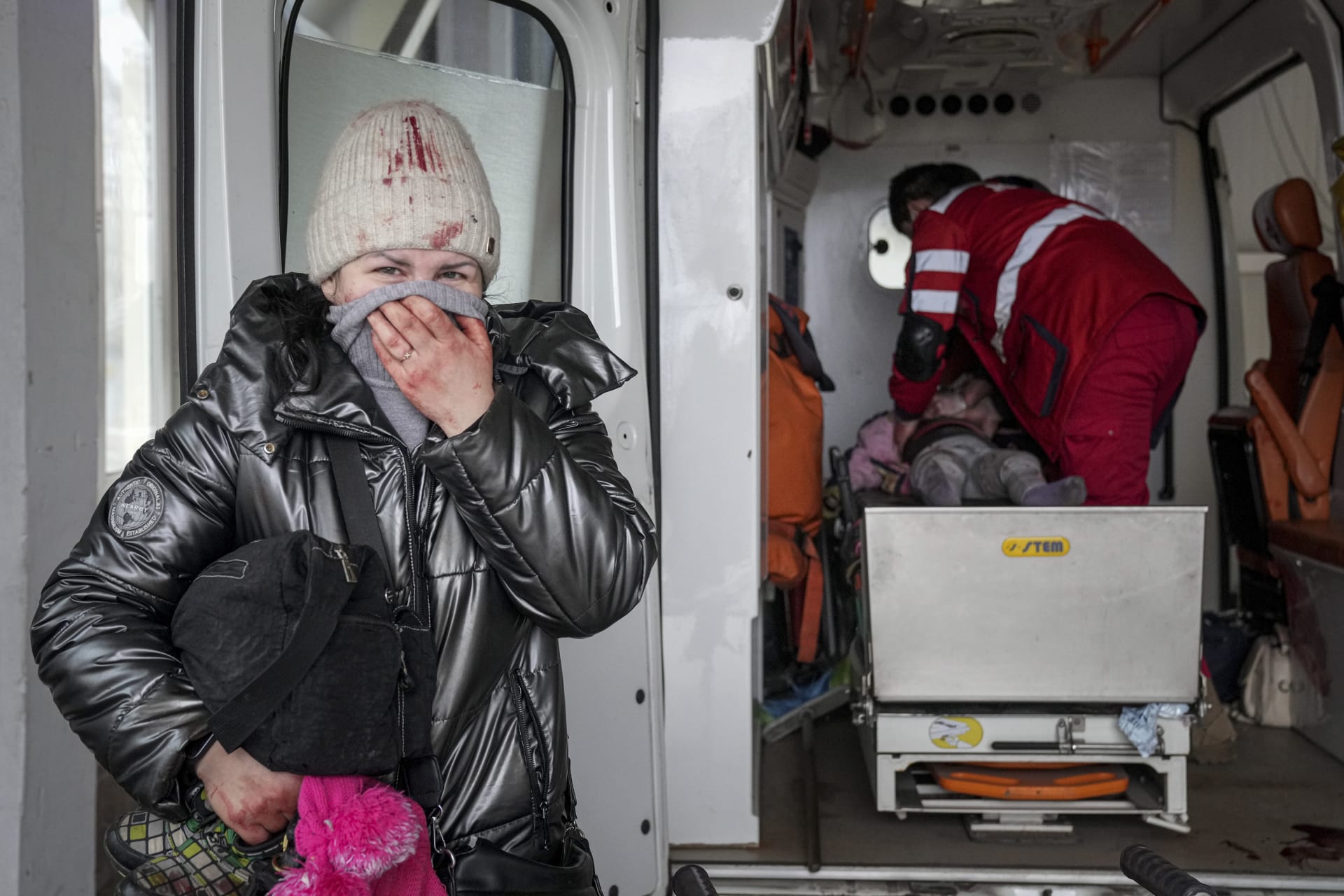 Žena reaguje, když zdravotníci provádějí resuscitaci dívky, která byla zraněna během ostřelování, v městské nemocnici v Mariupolu na východě Ukrajiny.