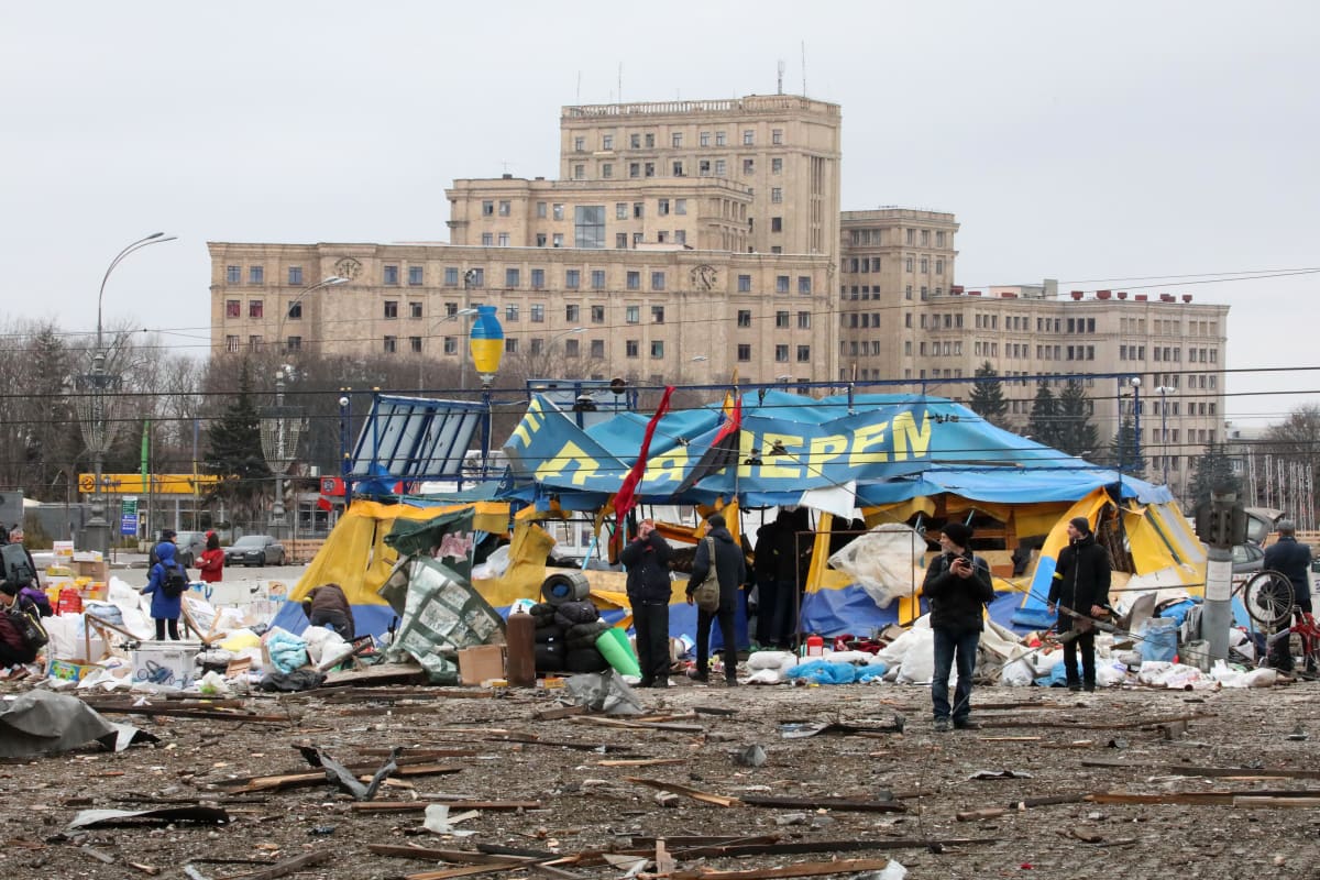 Lidé zůstávají u stanu dobrovolníků poté, co raketa odpálená ruskými útočníky dopadla před budovu charkovské oblastní státní správy na náměstí Svobody v úterý 1. března 2022.