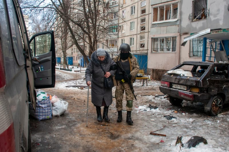 Ukrajinský voják pomáhá seniorce v Charkově.