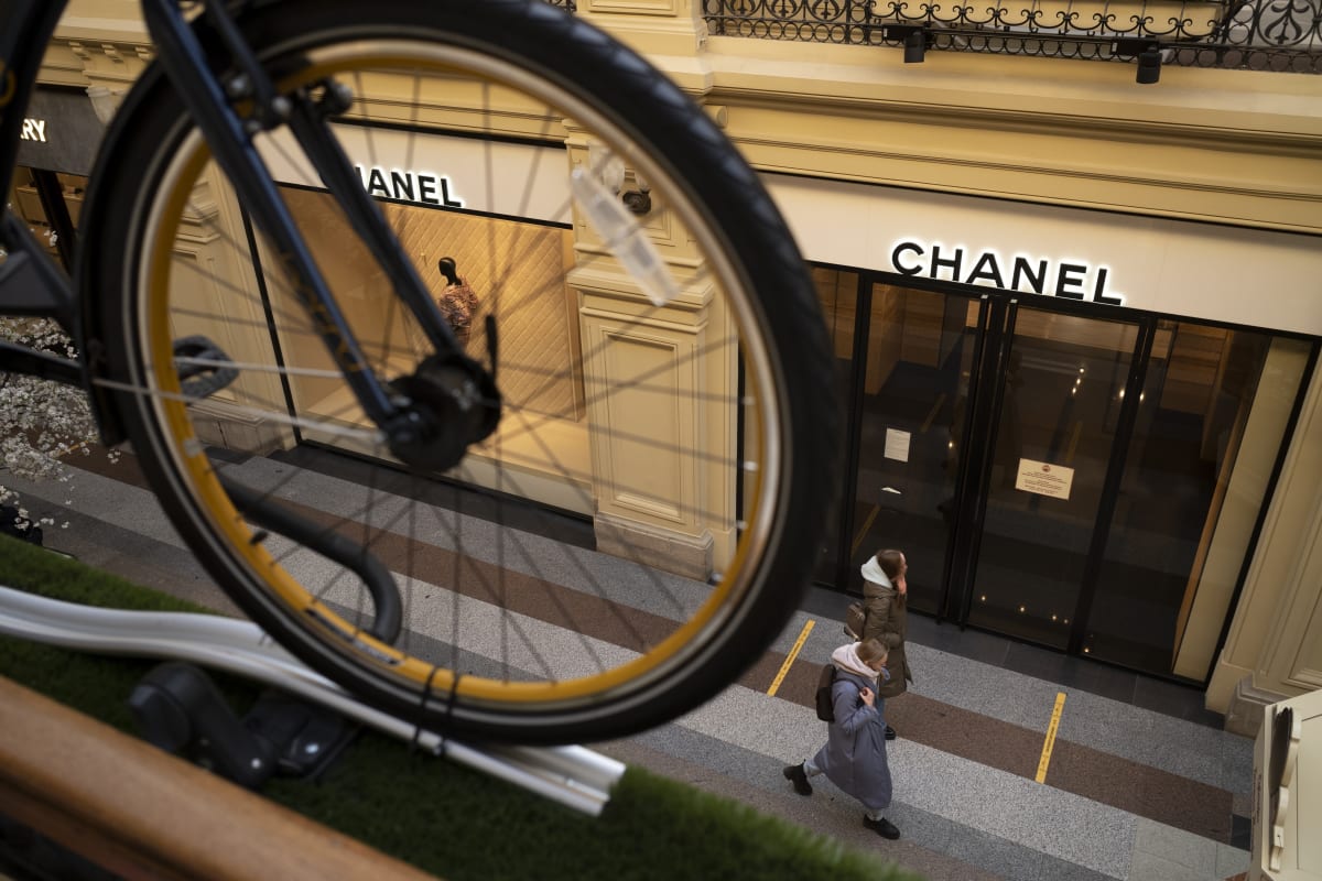 Lidé procházejí kolem zavřeného butiku Chanel v Moskvě. 