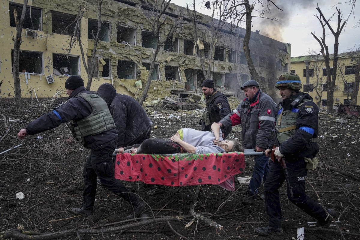 Dobrovolníci a bezpečnostní složky odnášejí zraněnou těhotnou ženu ze zbombardované ukrajinské porodnice v Mariupolu. Snímek z 9. března 2022.