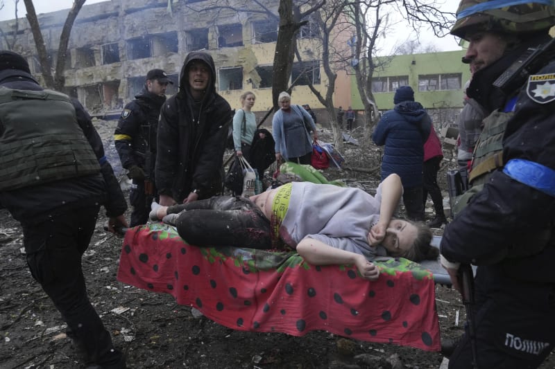 Dobrovolníci a bezpečnostní složky odnášejí zraněnou těhotnou ženu ze zbombardované ukrajinské porodnice v Mariupolu. Snímek z 9. března 2022.