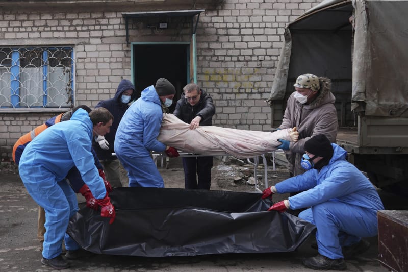 Záchranáři ukládají jednu z obětí bombardování do plastového pytle. Snímek z 9. března 2022.