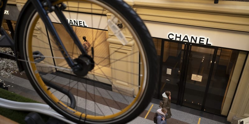 Lidé procházejí kolem zavřeného butiku Chanel v Moskvě. 