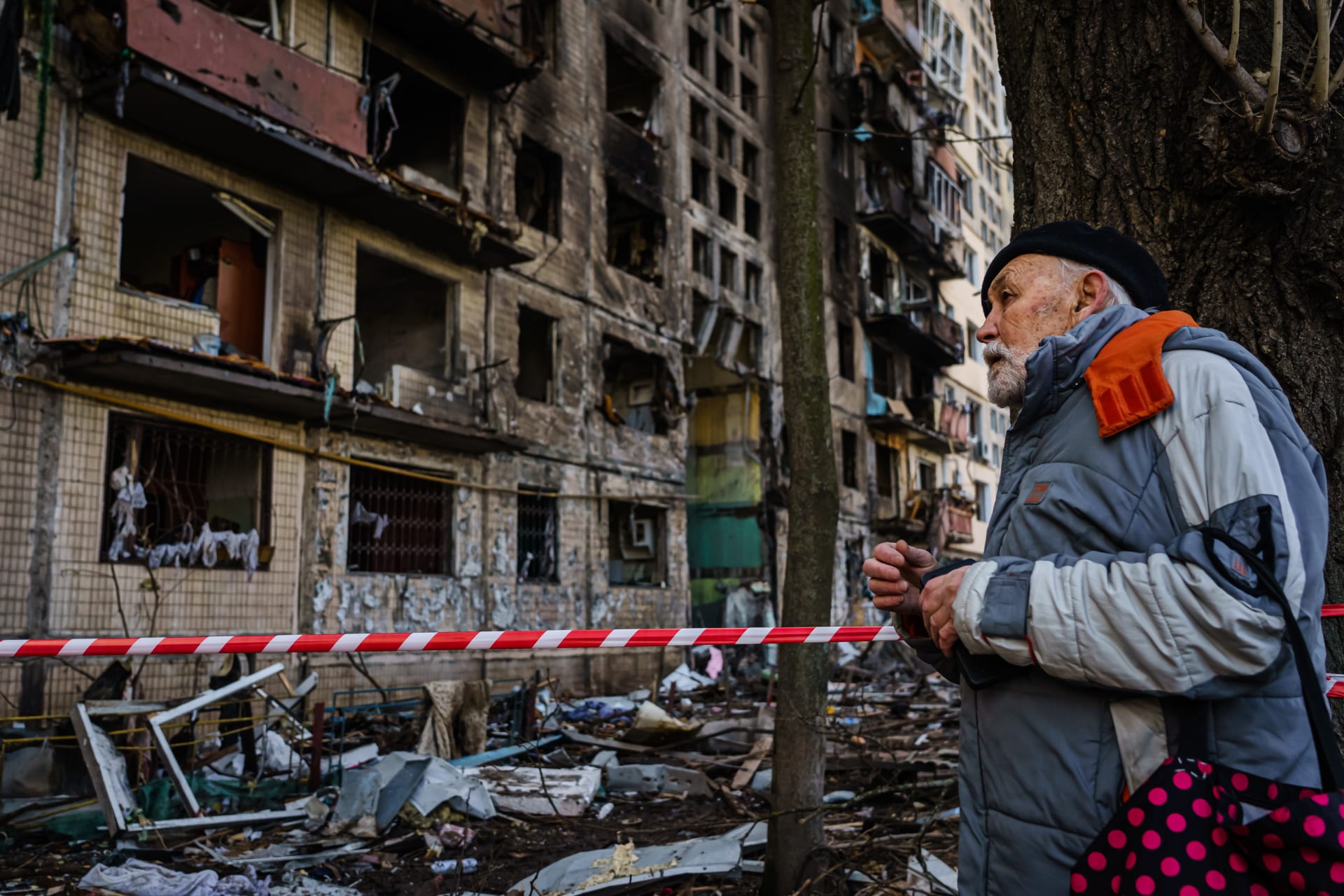 Muž se dívá na poškozený bytový dům, který byl podle kyjevských úřadů zasažen ruským bombardováním.