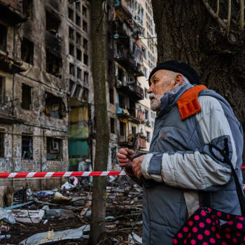 Muž se dívá na poškozený bytový dům, který byl podle kyjevských úřadů poškozen ruským bombardováním.
