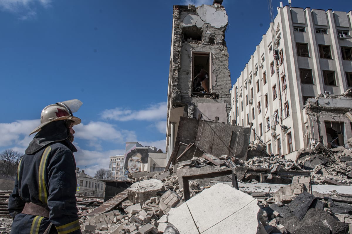 Záchranáři pracují na místě, kde se nachází Národní akademie státní správy, která je poškozená ostřelováním v Charkově. (18. března 2022)