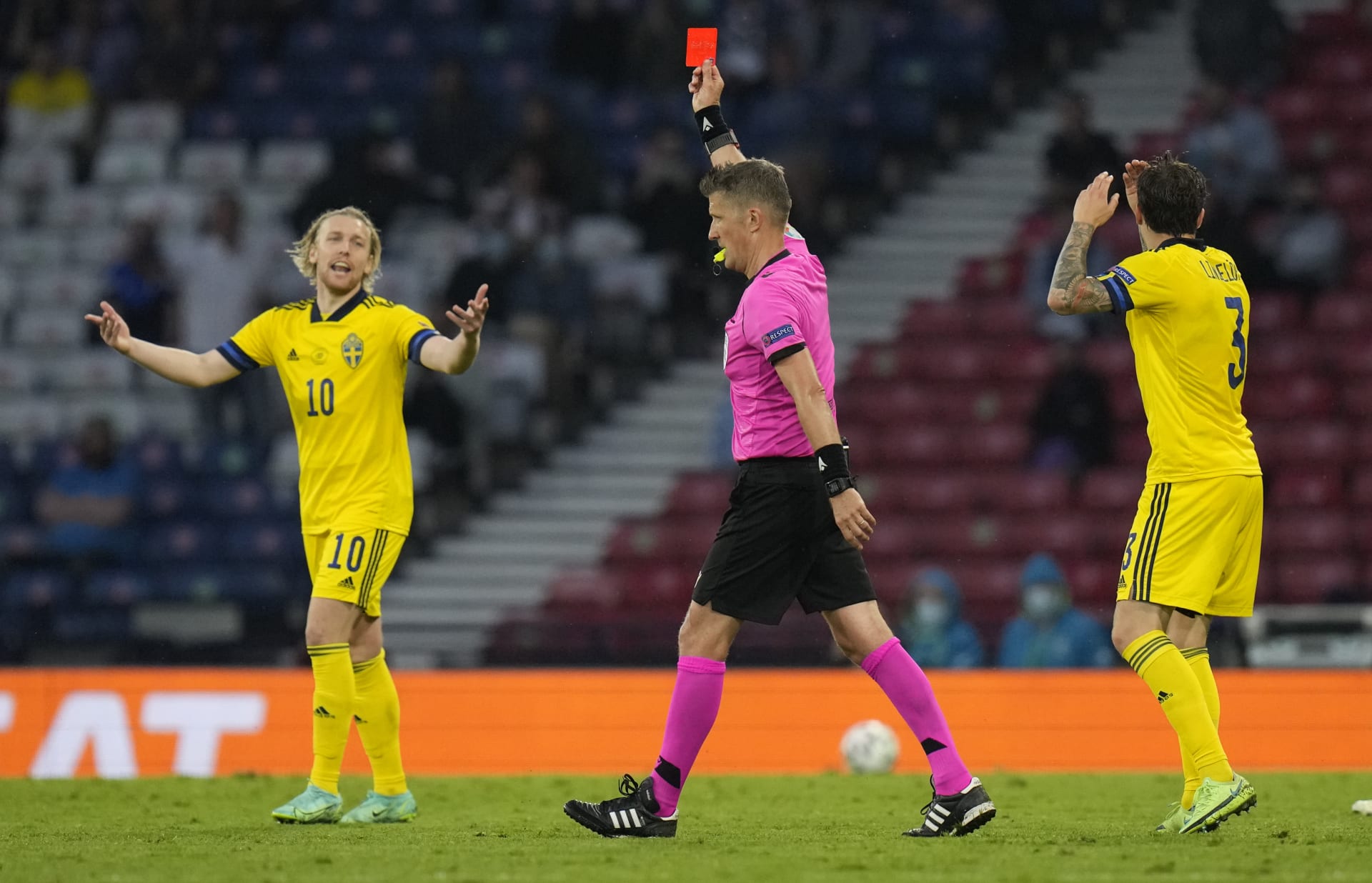 Švédský fotbalový útočník Emil Forsberg (vlevo) reaguje na červenou kartu, kterou italský rozhodčí Daniele Orsato udělil jeho spoluhráči Marcusi Danielsonovi při utkání mistrovství Evropy 2021 proti Ukrajině ve skotském Glasgowě.