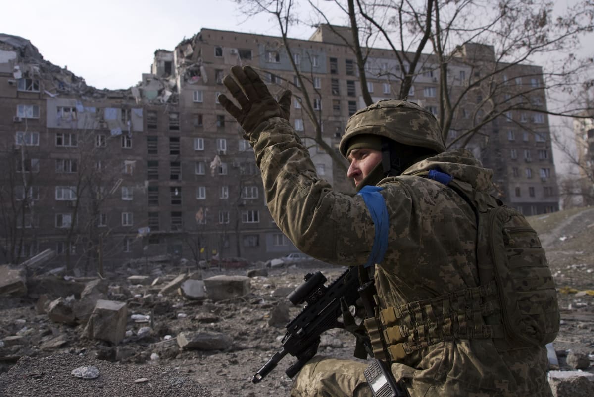 Ukrajinský voják u zničeného domu v Mariupolu (12. března 2022)