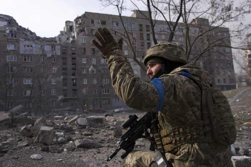 Ukrajinský voják u zničeného domu v Mariupolu