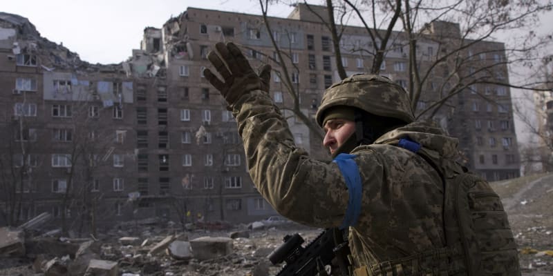 Ukrajinský voják u zničeného domu v Mariupolu (12. března 2022)