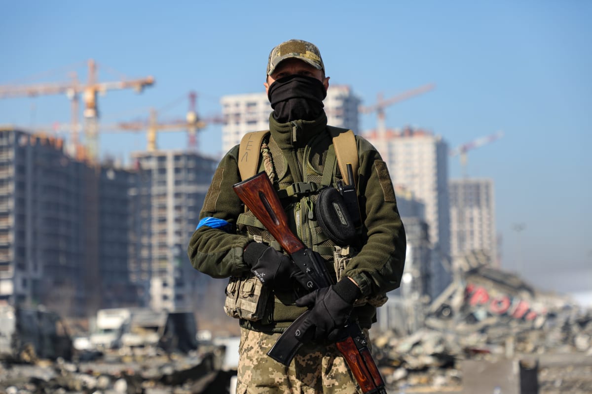 Voják je zachycen před obchodním centrem zničeným v důsledku raketového útoku ruských vojsk v Podilském okrese Kyjeva, hlavního města Ukrajiny. (23. března 2022)