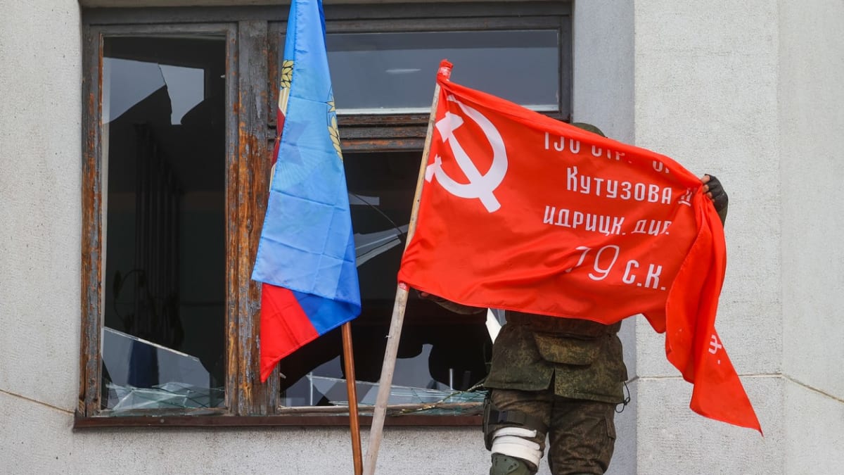 Člen milice Luhanské lidové republiky vyvěšuje vlajku na radnici ve městě Rubežnoje