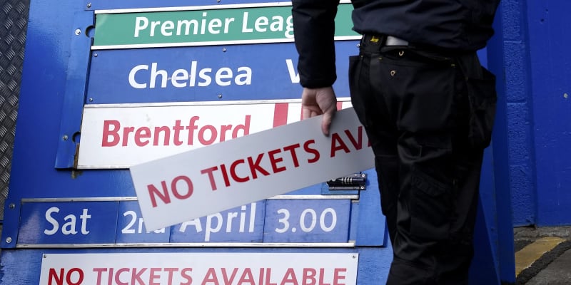 Zřízenec fotbalového klubu Chelsea Londýn odnáší cedulku „Vstupenky nejsou“ z tabule u vchodu stadionu Stamford Bridge poté, co britská vláda zmírnila sankce vůči majiteli Romanu Abramovičovi.